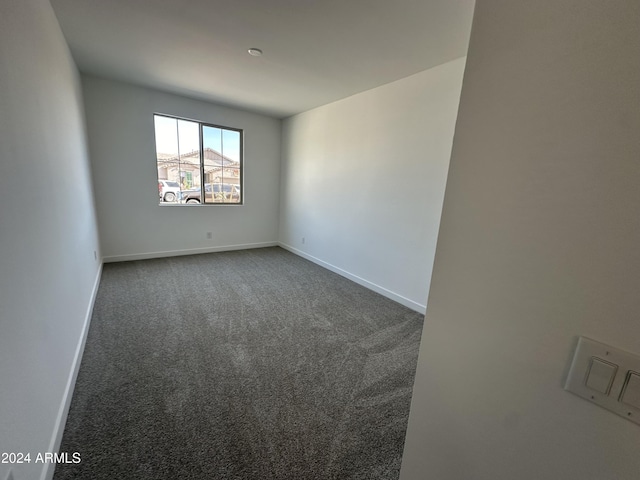 spare room featuring dark carpet