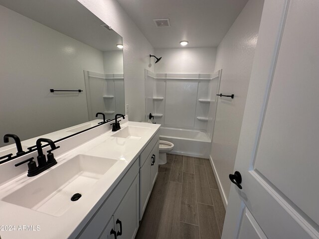 full bathroom with hardwood / wood-style flooring, vanity, toilet, and shower / washtub combination