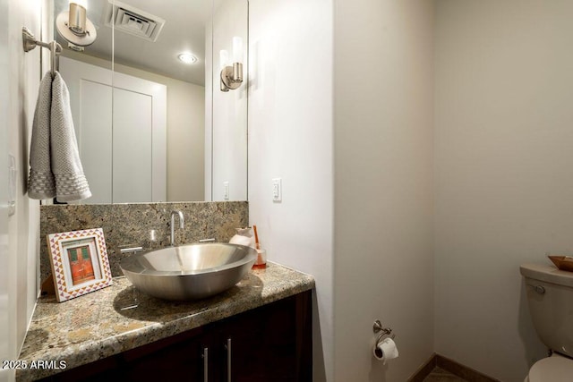 bathroom with vanity, backsplash, and toilet