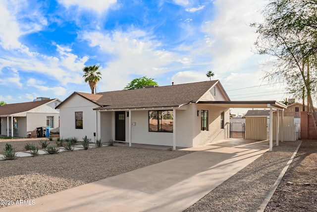 ranch-style house with roof with shingles, brick siding, a gate, concrete driveway, and a carport
