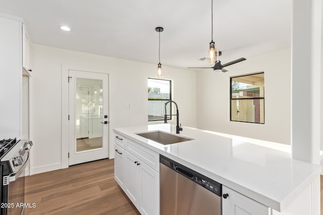 kitchen featuring white cabinets, hanging light fixtures, a sink, light wood finished floors, and stainless steel appliances