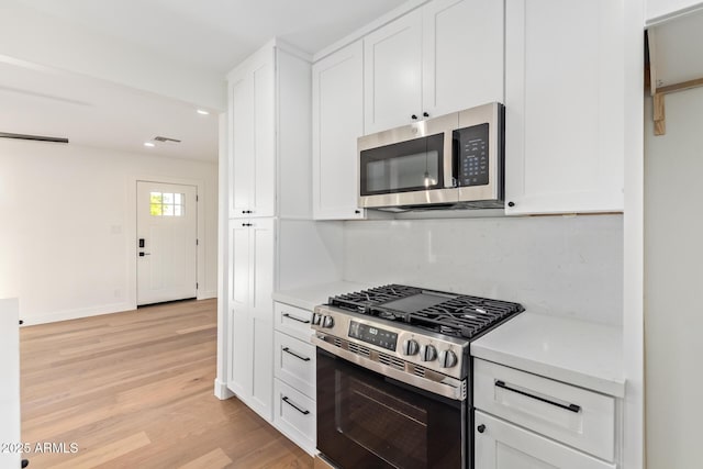 kitchen with appliances with stainless steel finishes, light countertops, white cabinetry, recessed lighting, and light wood-type flooring