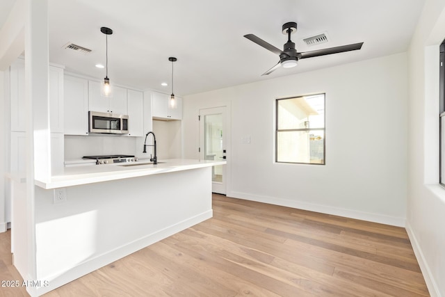 kitchen with ceiling fan, a sink, light wood finished floors, stainless steel microwave, and visible vents