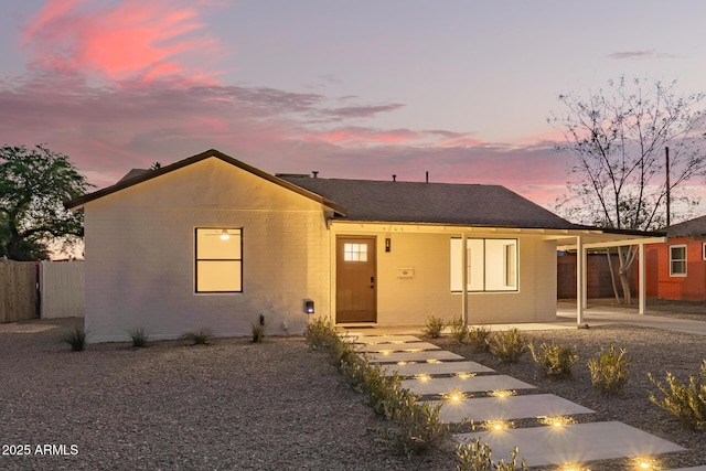 view of front of home featuring a shingled roof, an outdoor fire pit, fence, and an attached carport