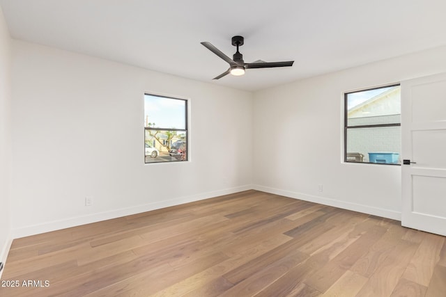 unfurnished room with a ceiling fan, baseboards, and light wood-style flooring