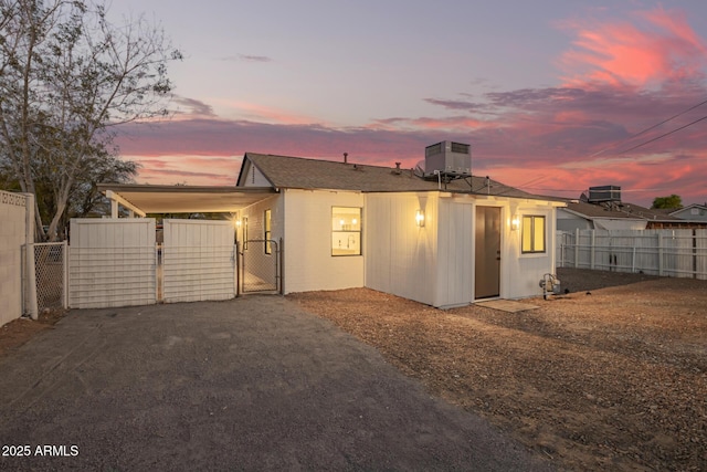 view of front facade with driveway, fence, central AC unit, and a gate