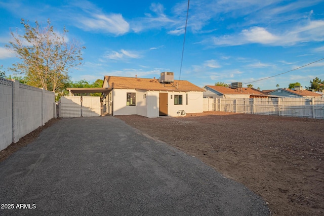 back of property with central air condition unit, driveway, a fenced backyard, and stucco siding