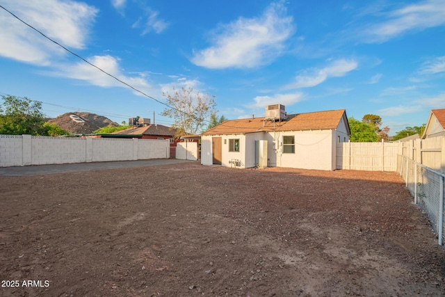 back of property with central AC unit and a fenced backyard