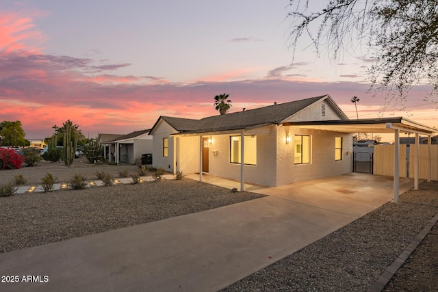 ranch-style home with a gate, brick siding, fence, concrete driveway, and an attached carport