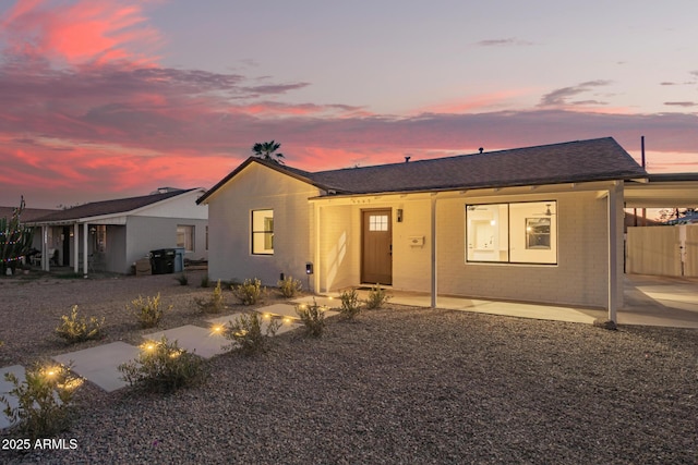 ranch-style home featuring a shingled roof, an attached carport, and brick siding