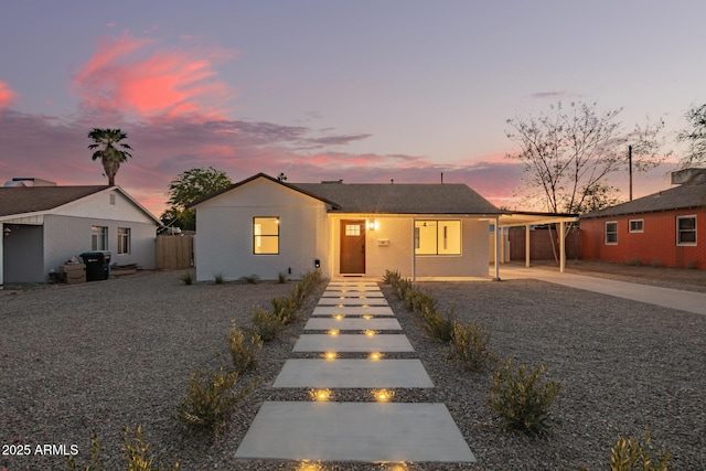 view of front of property with concrete driveway, fence, and a carport