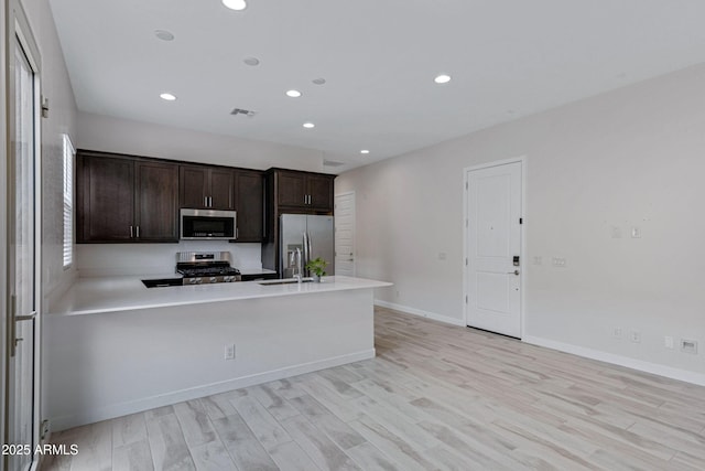 2968 E Tundra Ln, San Tan Valley, AZ 85143 - kitchen with light countertops, a peninsula, stainless steel appliances, dark brown cabinets, and a sink