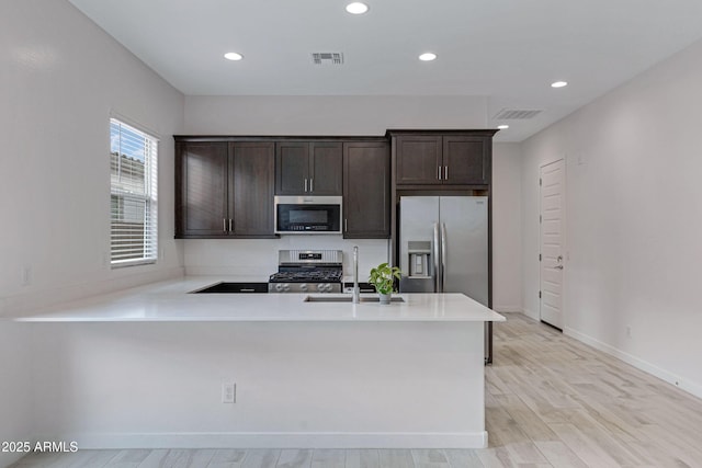 2968 E Tundra Ln, San Tan Valley, AZ 85143 - kitchen with dark brown cabinetry, a sink, a peninsula, stainless steel appliances, and visible vents