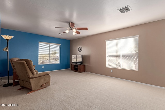 living area featuring light carpet and ceiling fan