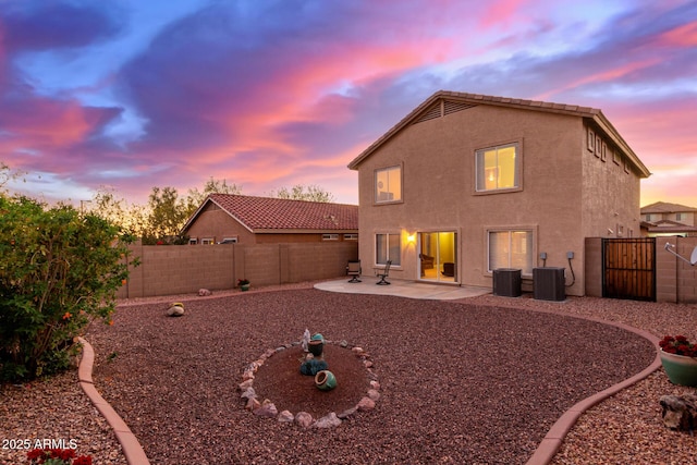 back house at dusk featuring cooling unit and a patio