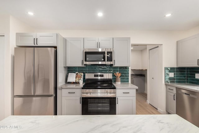 kitchen with tasteful backsplash, stainless steel appliances, and light stone counters