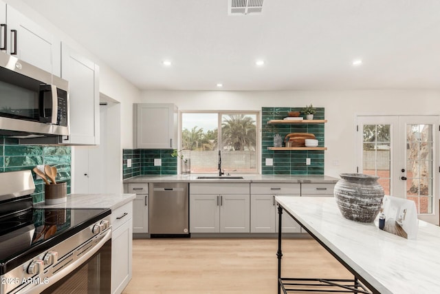 kitchen featuring french doors, sink, tasteful backsplash, light hardwood / wood-style flooring, and appliances with stainless steel finishes