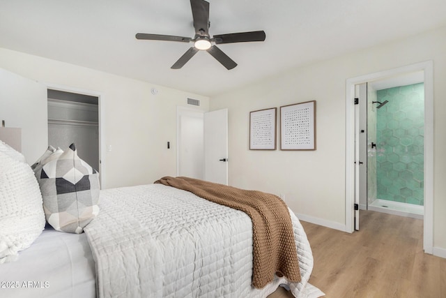 bedroom with ceiling fan, connected bathroom, light wood-type flooring, and a closet