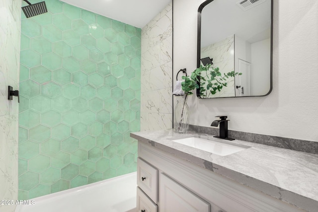 bathroom with tiled shower / bath combo and vanity