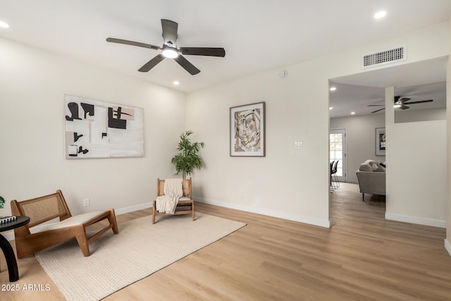 living area featuring hardwood / wood-style flooring and ceiling fan