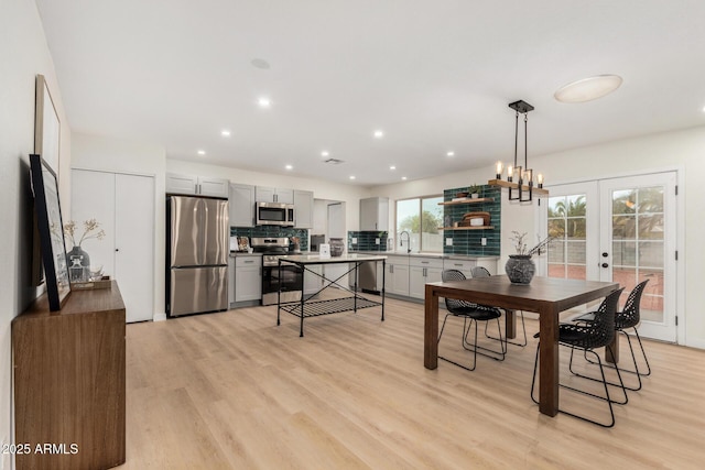 dining space with sink, light wood-type flooring, and french doors