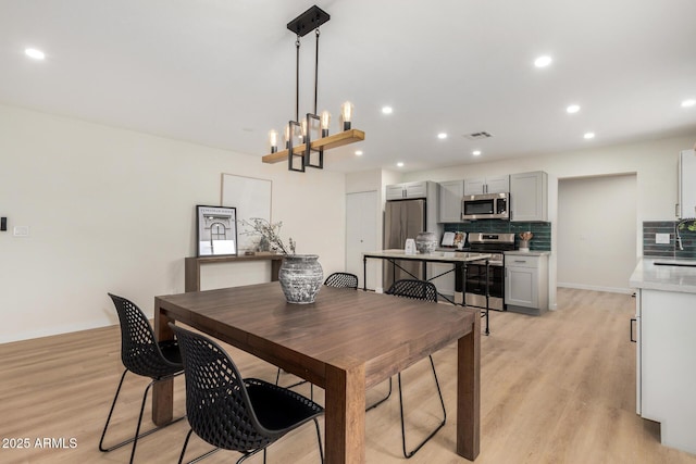 dining space featuring sink, a notable chandelier, and light hardwood / wood-style floors