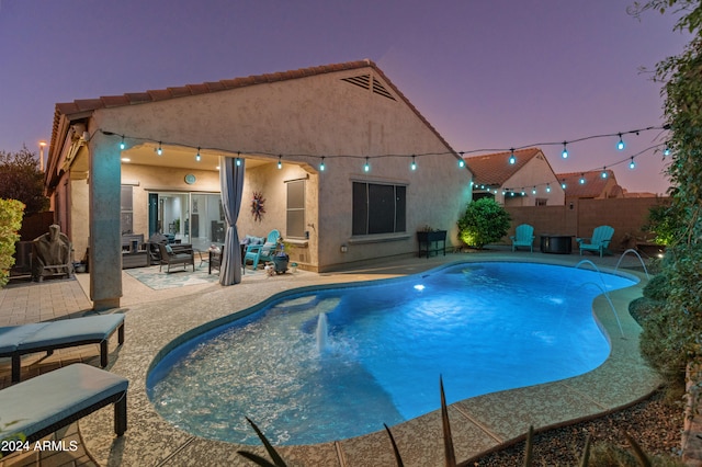 pool at dusk featuring pool water feature and a patio area