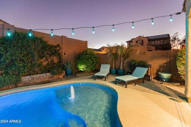 pool at dusk with a patio area