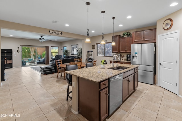 kitchen featuring stainless steel appliances, light stone counters, sink, a kitchen island with sink, and ceiling fan