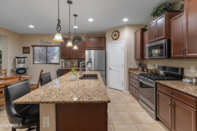 kitchen with appliances with stainless steel finishes, a center island with sink, sink, and a breakfast bar