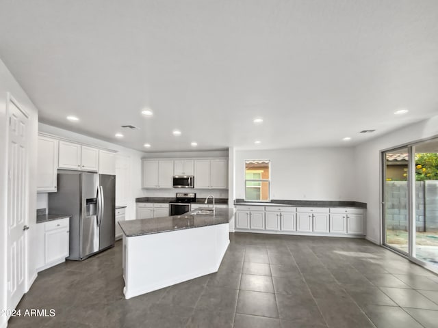 kitchen with white cabinets, stainless steel appliances, a center island with sink, and sink