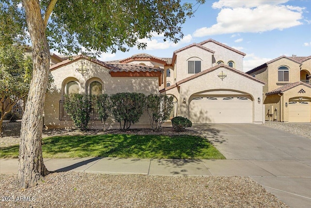 mediterranean / spanish house featuring an attached garage, stucco siding, driveway, and a tiled roof