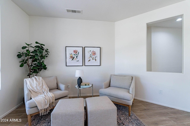 living area featuring wood tiled floor, visible vents, and baseboards