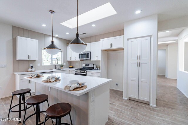 kitchen featuring stainless steel appliances, a kitchen bar, sink, a kitchen island, and hanging light fixtures