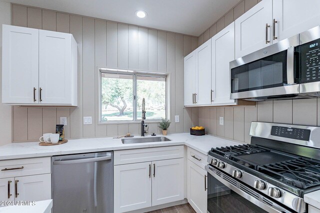 kitchen featuring sink, stainless steel appliances, white cabinets, and light stone countertops