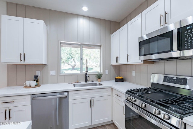 kitchen featuring light stone countertops, white cabinetry, stainless steel appliances, and a sink