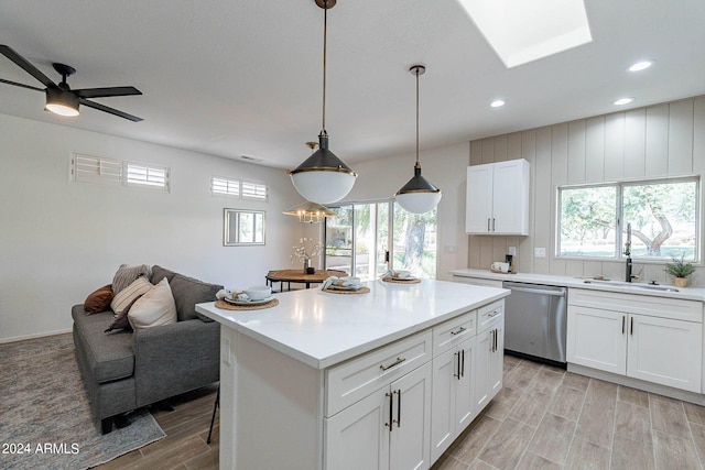 kitchen with wood finish floors, a sink, white cabinetry, stainless steel dishwasher, and a center island