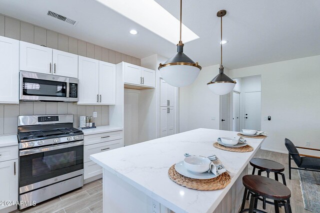 kitchen featuring white cabinetry, a center island, stainless steel appliances, and decorative backsplash