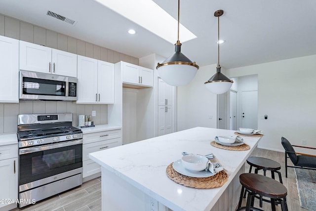 kitchen featuring visible vents, appliances with stainless steel finishes, wood tiled floor, white cabinetry, and backsplash