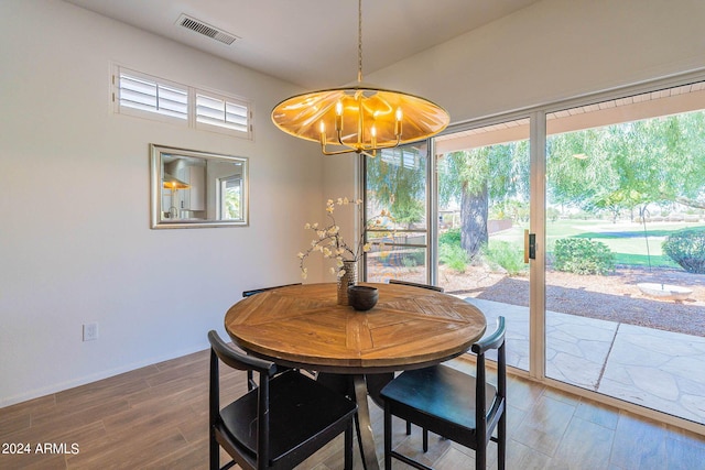 dining area with wood finished floors, visible vents, and an inviting chandelier