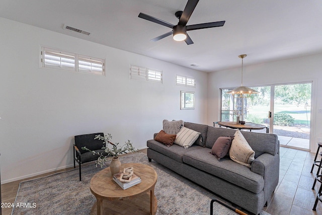 living room with ceiling fan, visible vents, and baseboards