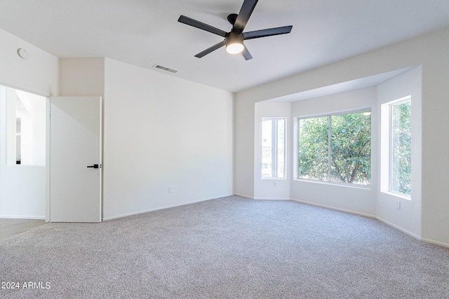 carpeted spare room with a ceiling fan, visible vents, and baseboards