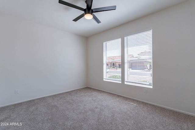 carpeted spare room featuring a ceiling fan and baseboards