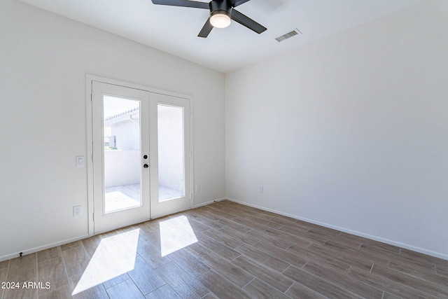 empty room with ceiling fan, hardwood / wood-style flooring, and french doors