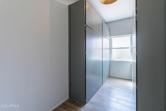 corridor with light wood finished floors and baseboards