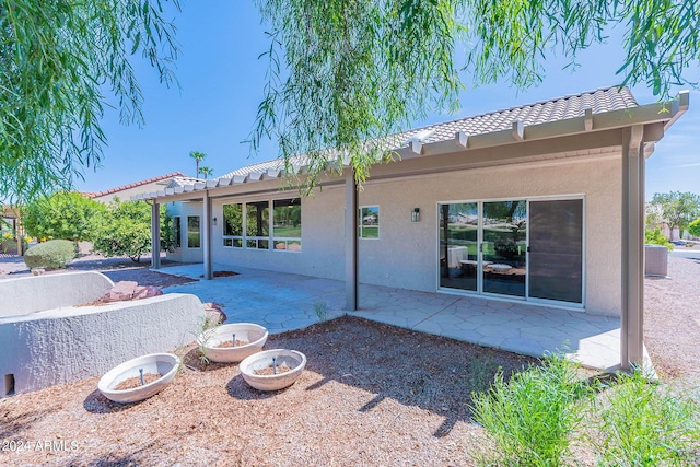 rear view of property with a patio area, a tile roof, an outdoor fire pit, and stucco siding