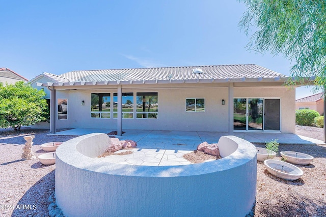 rear view of property featuring stucco siding, a patio area, and a tiled roof