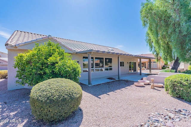 view of front of property with a patio, a tile roof, and stucco siding