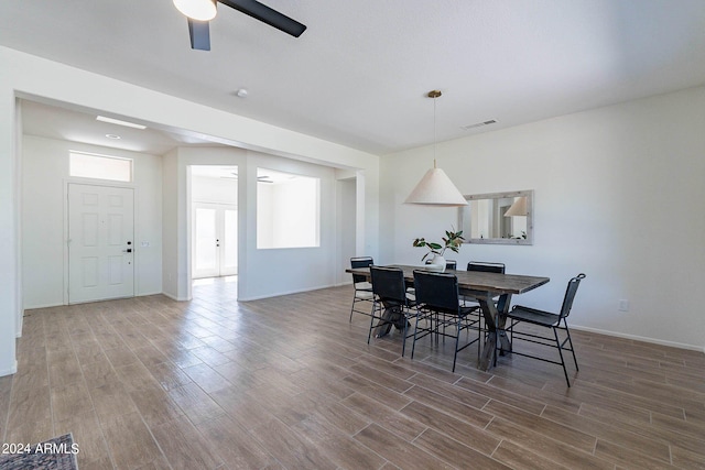 dining room featuring baseboards, ceiling fan, visible vents, and wood finished floors