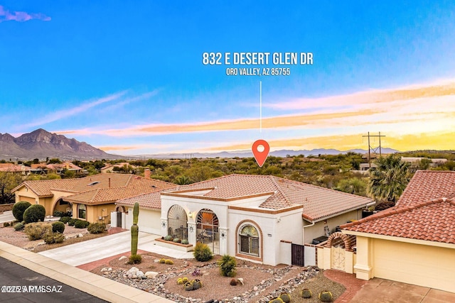 view of front of home with a mountain view, a tiled roof, driveway, a gate, and stucco siding